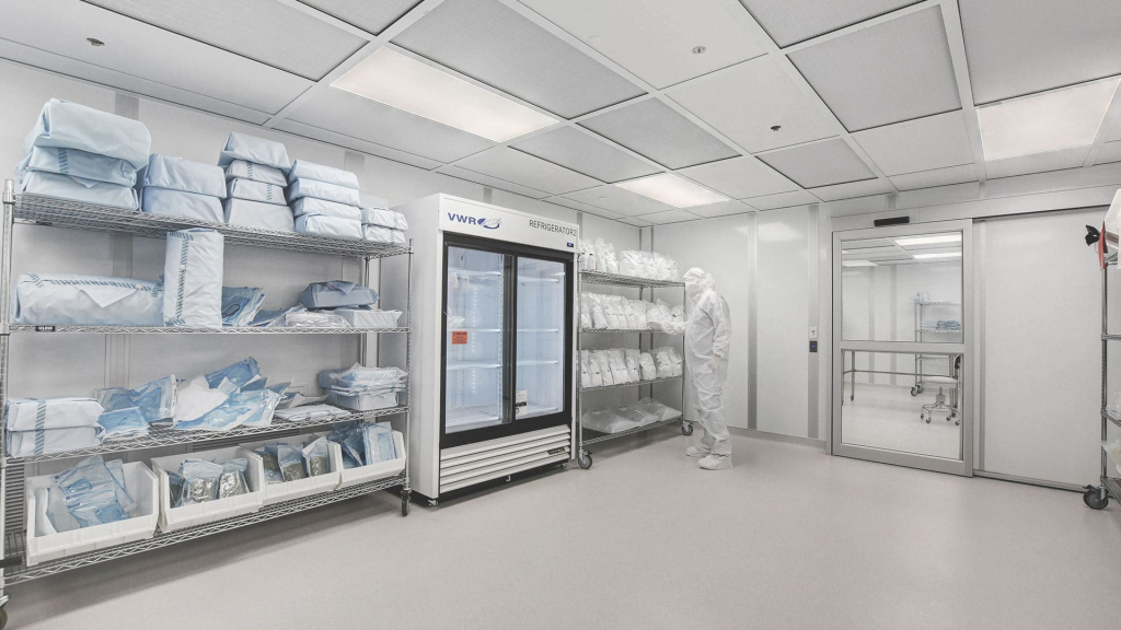 How Much Does a Cleanroom Cost? A Simple Guide Inside a cleanroom, a person in protective gear organizes sterile supplies on shelves next to a refrigerator.