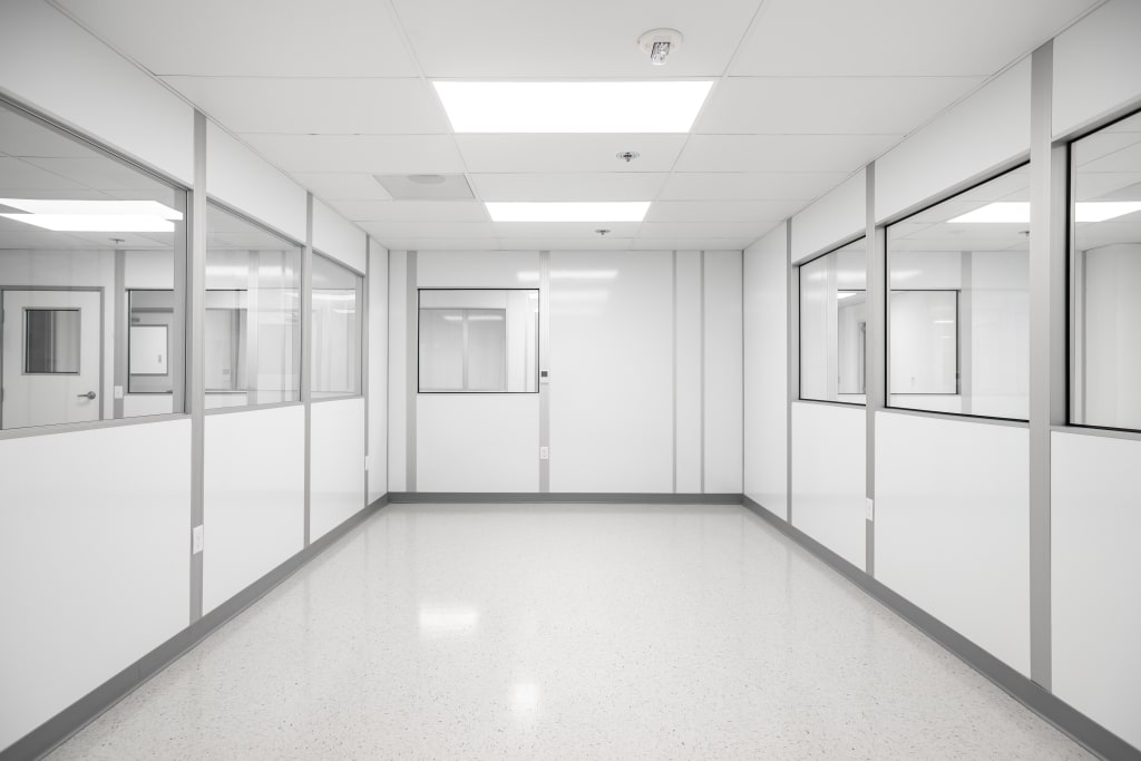 Cleanroom Requirements for Pharmaceuticals: A Short Guide Modular cleanroom by Allied Cleanrooms featuring white panel walls, large interior windows, a polished seamless floor, and a grid ceiling with integrated lighting—designed for controlled environments in pharmaceutical or laboratory settings.