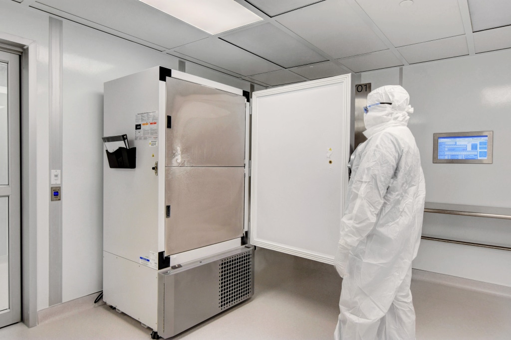 White Rooms: Features, Uses, and Best Practices Technician in clean gown operating equipment inside an Allied Cleanrooms modular white room with wall-mounted control panel.