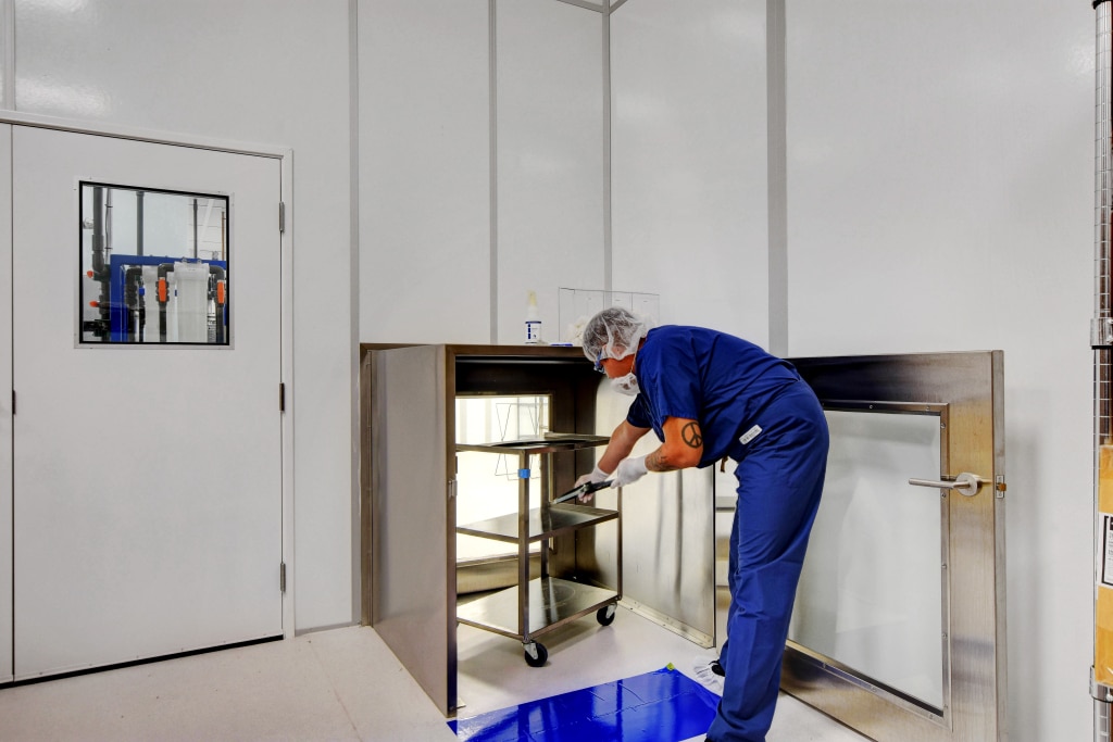 What are ISO Cleanroom Standards? Why are They Important? A cleanroom technician in protective garments is using a pass-through chamber to maintain sterile conditions.
