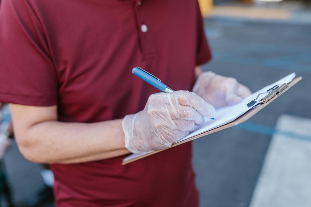 Post-Build Cleanroom Planning: What to Know Early On Person wearing gloves writes on a clipboard during a cleanroom testing inspection for GMP compliance for cleanrooms (at Allied Cleanrooms).