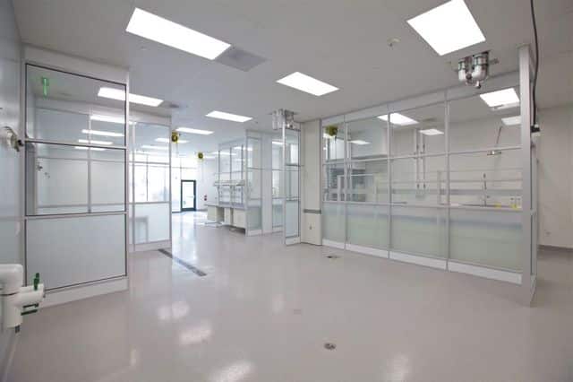 What are Pharmaceutical Cleanrooms? The Ultimate Guide Spacious pharmaceutical cleanroom with glass partition walls, integrated workstations, and overhead utility supplies, designed for precision manufacturing and quality control.
