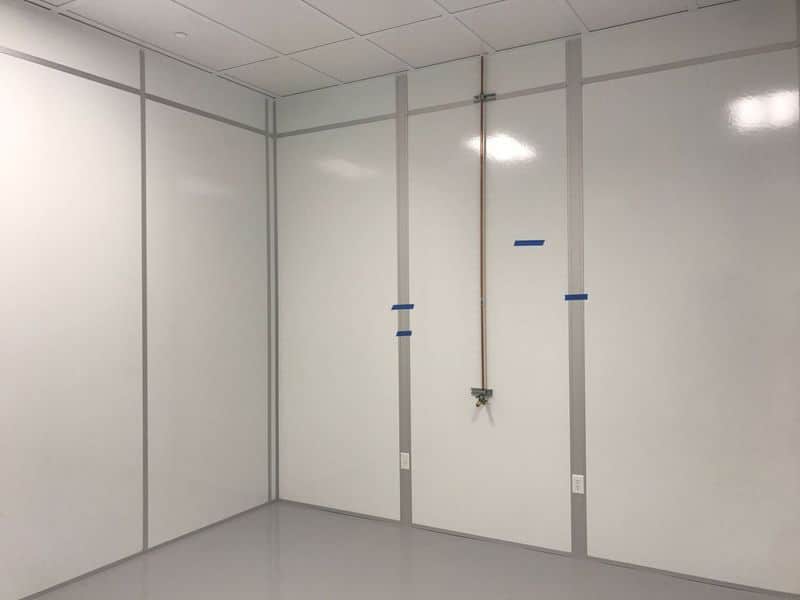 Cleanroom Walls: A Look at Materials and Systems Cleanroom walls featuring smooth FRP (Fiberglass Reinforced Plastic) panels with metal trim and utility connections.