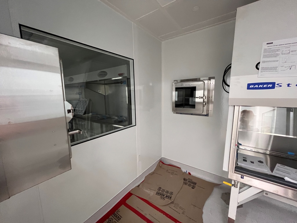 White Rooms: Features, Uses, and Best Practices Interior of a modular white room by Allied Cleanrooms, featuring a pass-through chamber, observation window, and work station.