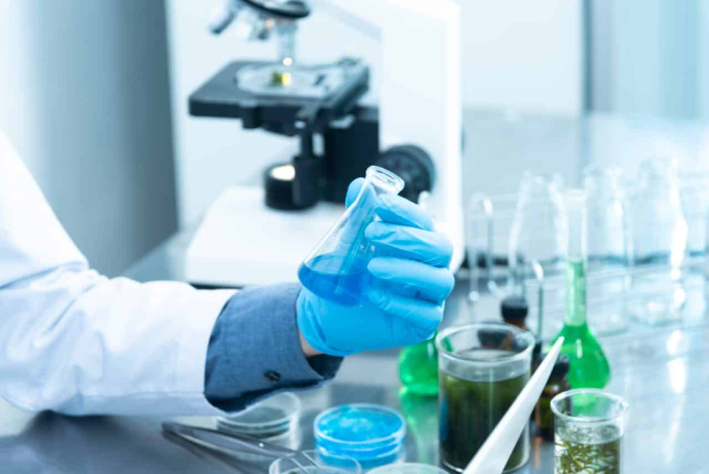 Types of Medical Cleanrooms You Should Know A scientist conducting medical research and holding a beaker of blue liquid.