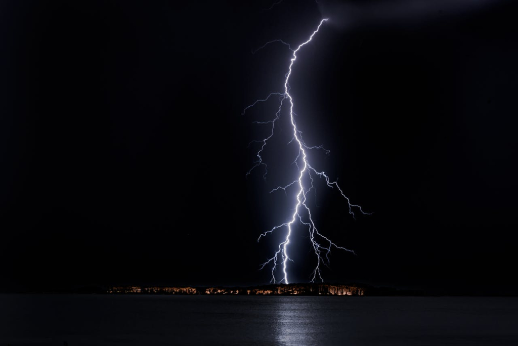 ESD Control in Cleanrooms: A Simple Guide A powerful lightning bolt striking the ground over a body of water at night, illustrating a natural example of electrostatic discharge (ESD).
