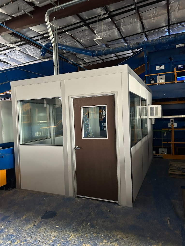 A modular warm-up room in an industrial facility, equipped with windows and an air conditioning unit for temperature control.
