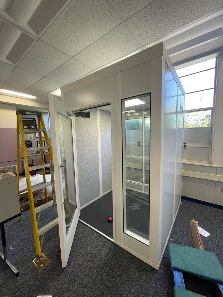 A modular cool-down booth with glass windows and an open door, designed for temperature control in industrial or manufacturing environments.
