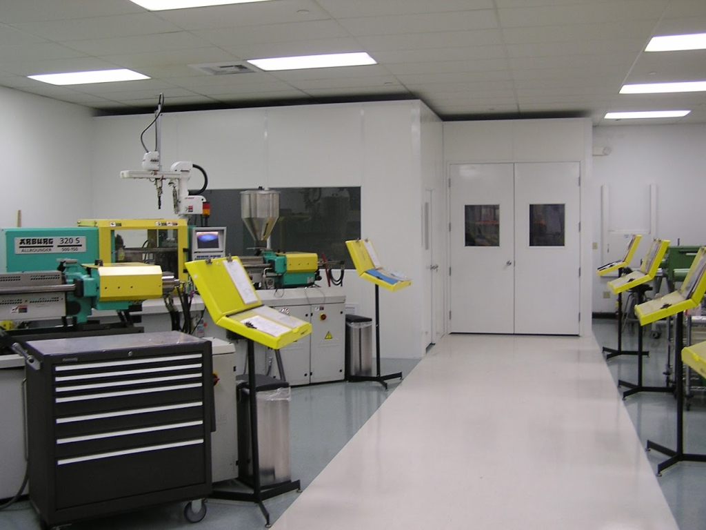 Electronics Cleanrooms 101: Everything You Need to Know Cleanroom featuring injection molding machines, workstations with control panels, and a modular design for precision manufacturing in a controlled environment.