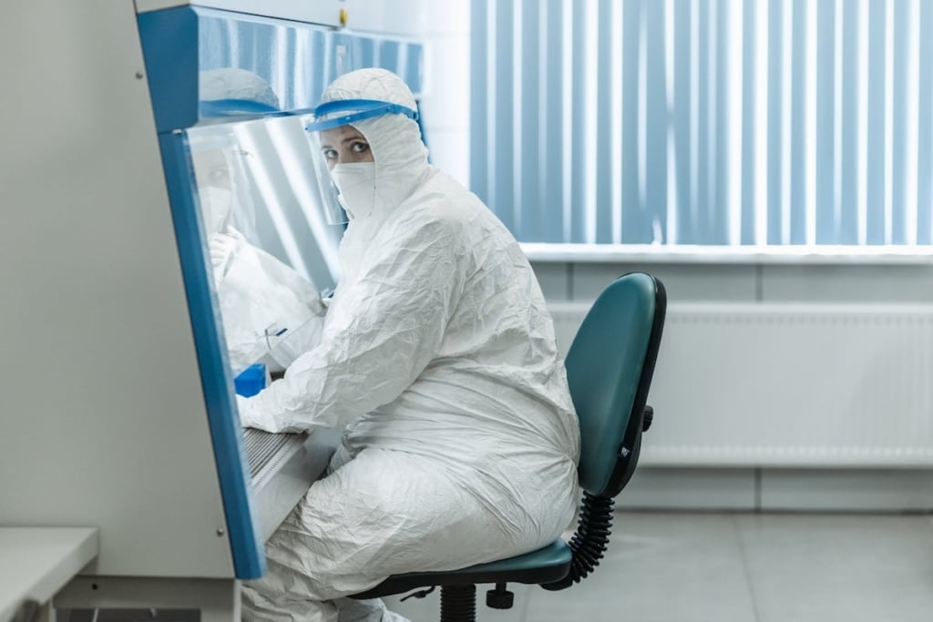 Cleanroom Maintenance: Daily Tasks to Prevent Contamination Technician in full cleanroom gowning seated at workstation inside an Allied Cleanrooms modular cleanroom